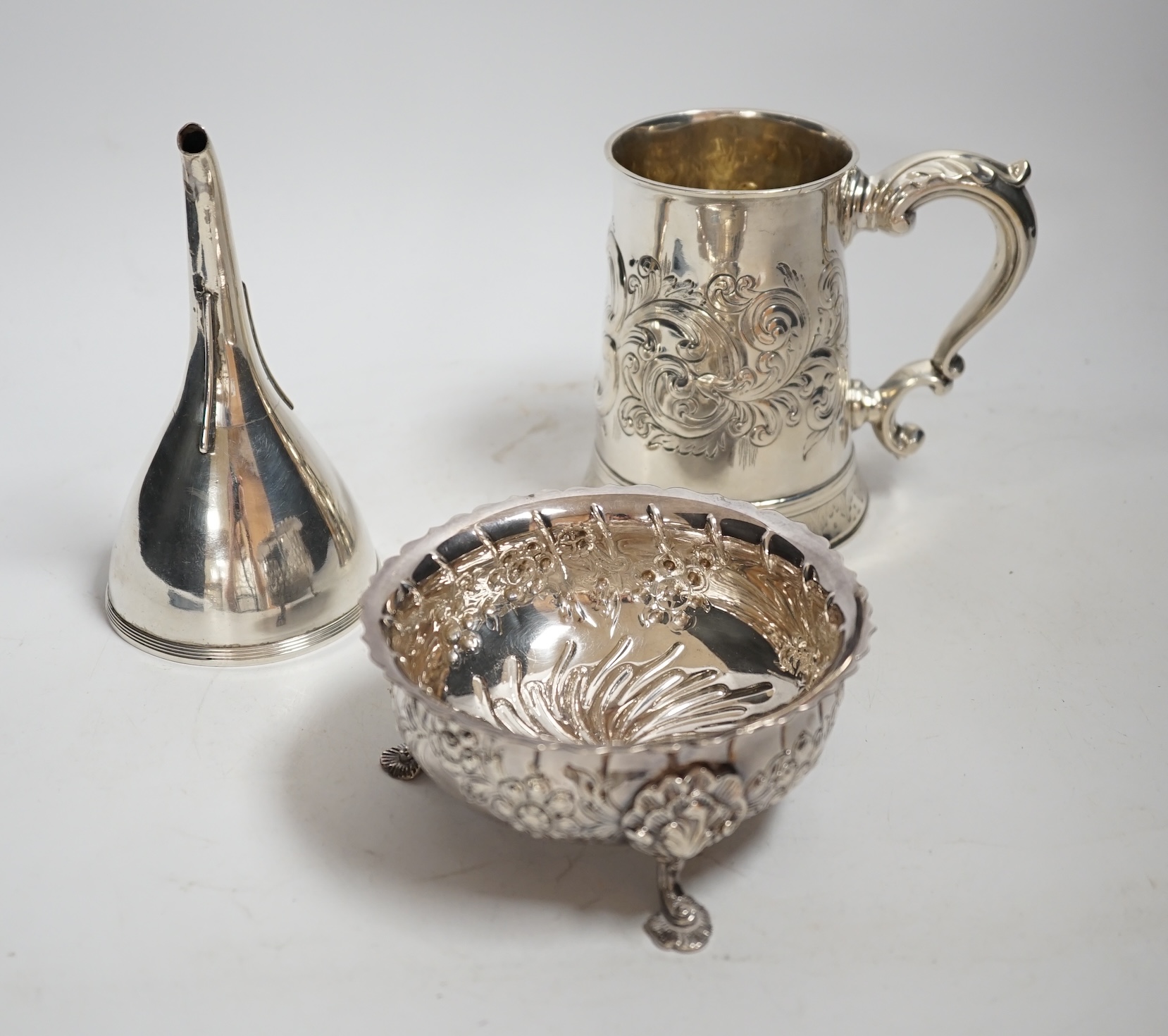 A George III silver mug, with later embossed decoration, London, 1783,11.6cm, together with a George III silver wine funnel and a modern Irish silver sugar bowl, 21.5oz.